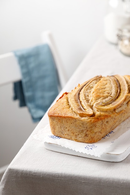 Pain aux bananes fait maison sur une planche de bois sur une table avec une nappe