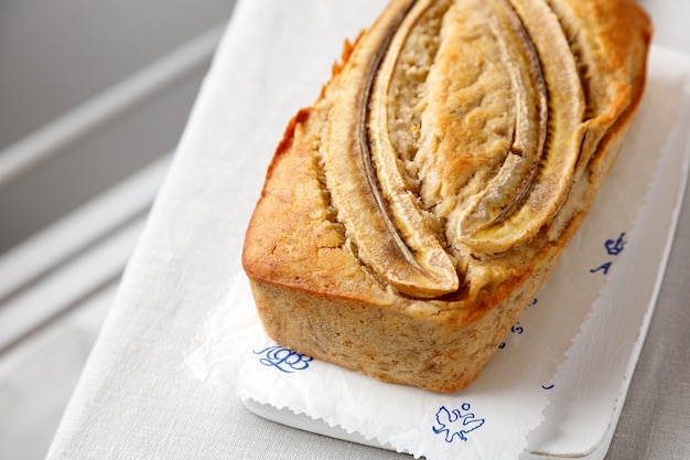 Pain aux bananes fait maison sur une planche de bois sur une table avec une nappe