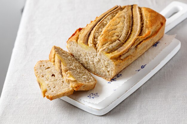 Pain aux bananes fait maison sur une planche de bois sur une table avec une nappe