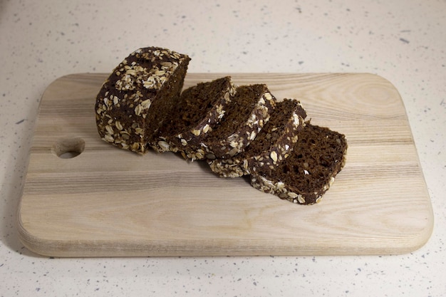 Pain aux céréales fraîchement cuit sur une planche à découper en bois sur un fond de marbre clair gros plan