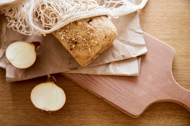 Pain aux oignons sans levain biologique sur du papier kraft sur une planche de bois de coupe de cuisine Miche de pain naturel fraîchement cuit Fond de nourriture rustique beige