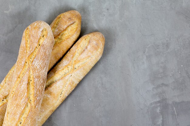 Photo pain baguette français sur fond de béton gris copyspace en diagonale pour le texte