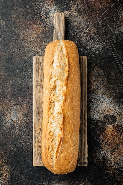 Pain baguette à grains entiers, sur fond rustique sombre, vue de dessus à plat