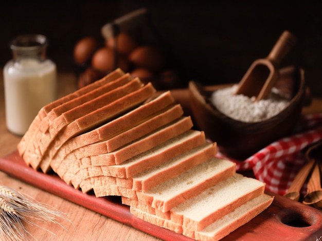 Pain blanc en tranches de pain grillé (Shokupan ou Roti Tawar) pour le petit déjeuner sur fond de bois, servi avec des œufs et du lait. Image de concept de boulangerie