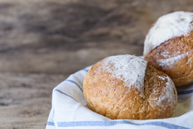 Pain de blé entier situé dans un panier en bambou sur fond de table en bois