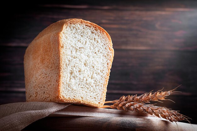 Pain de blé naturel fait maison servi sur une planche à découper en bois avec un ingrédient de grains mûrs