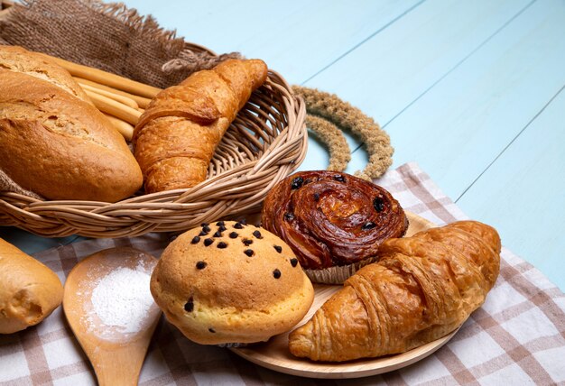 Pain de boulangerie sur une table en bois bleue. Divers pain et gerbe d'épis de blé.