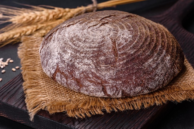 Pain brun fait maison frais sur un fond de béton noir avec des grains de blé