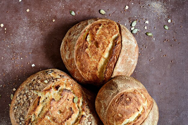 Pain de campagne fraîchement cuit fait maison à base de blé et de farine de grains entiers sur fond brun.