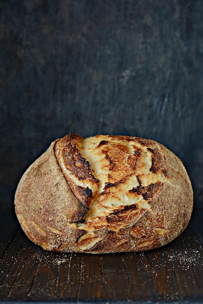 Pain De Campagne Fraîchement Cuit Fait Maison à Base De Blé Et De Farine De Grains Entiers Sur Un Fond Sombre. Pain Français Fraîchement Sorti Du Four. Trancher Du Pain Maison