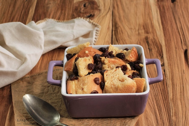 Pain à la cannelle et pudding au beurre avec des raisins secs dans un plat de cuisson carré violet, espace de copie pour le texte