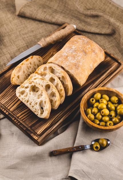 Pain ciabatta frais sur une planche de bois aux olives