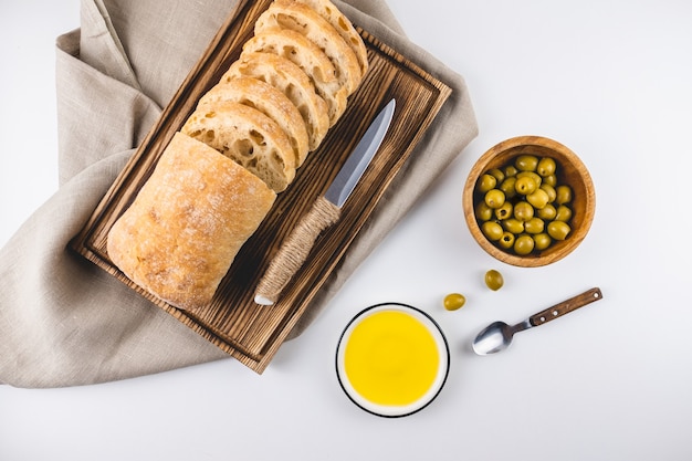 Pain ciabatta frais sur une planche en bois avec olives et huile d'olive