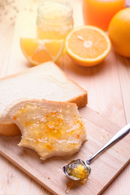 Pain avec confiture d&#39;orange et jus d&#39;orange sur la table en bois