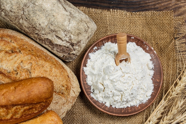 Pain croustillant frais avec de la farine sur une table en bois