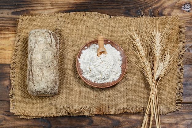 Pain croustillant frais avec de la farine sur une table en bois