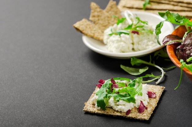 Pain croustillant avec mélange de légumes verts frais et de fromage à la crème sur fond noir