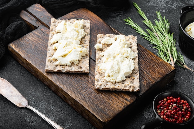 Pain croustillant de seigle entier avec ensemble de fromage à la crème, sur une table en pierre noire noire