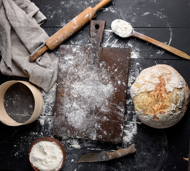 Pain cuit au four, farine de blé blanche, rouleau à pâtisserie en bois et vieille planche à découper