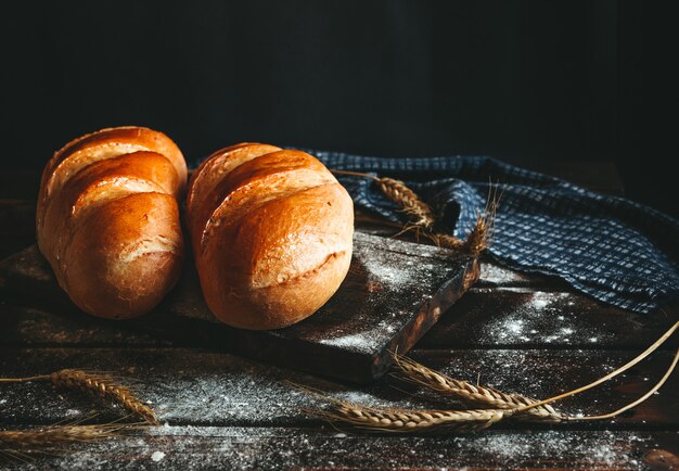 Pain cuit sur une table rustique en farine et épis de blé