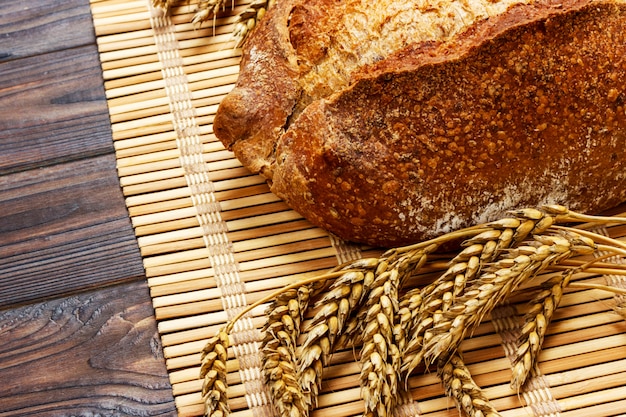 Pain entier fait maison avec du blé sur un fond en bois