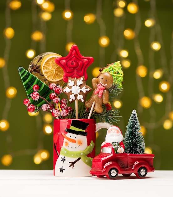 Pain d'épice de Noël et bonbons sur des bâtons dans une tasse cadeau rouge et Père Noël sur une petite voiture rouge. Joyeux noël carte de fête avec des bonbons et des décorations