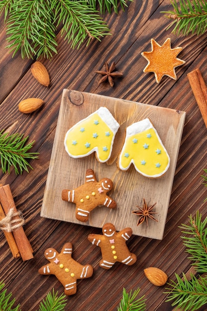 Photo pain d'épice de noël fait maison avec des branches de sapin et des épices sur fond de bois, vue de dessus, mise en page à plat. composition de vacances avec pâtisserie artisanale.