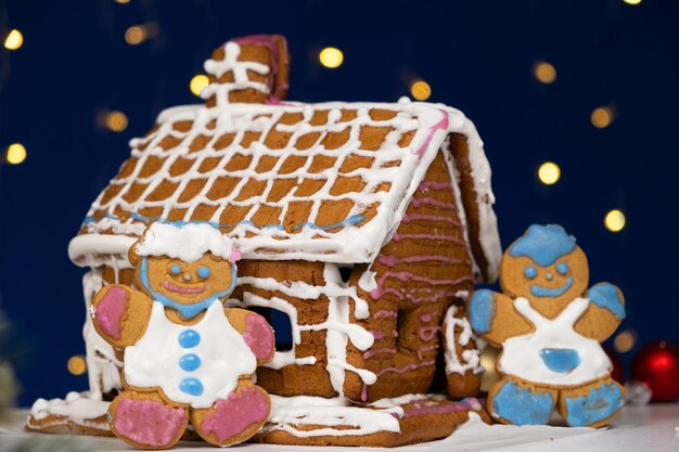 Le pain d'épice de Noël en forme d'homme est décoré d'un glaçage au sucre coloré et d'une maison de biscuits