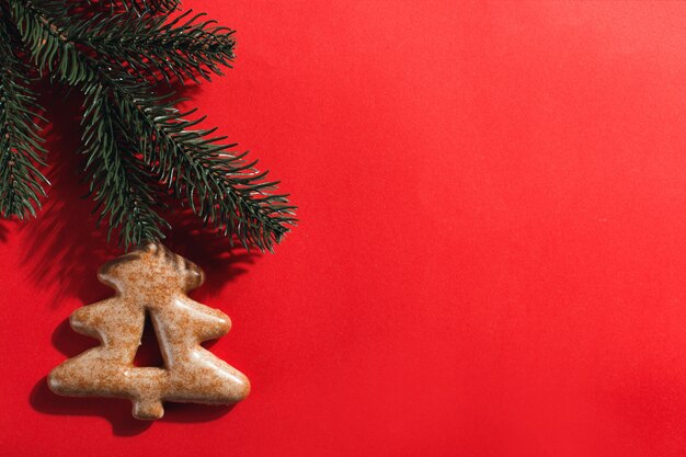 Pain d'épice de Noël sous la forme d'un arbre de Noël sur un fond rouge, surface.