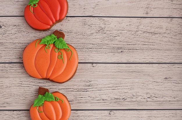 Photo pain d'épice peint à la main sous forme de citrouilles sur un fond en bois clair