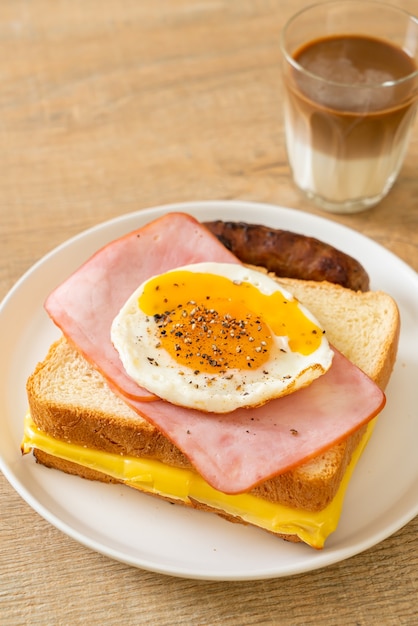 Pain fait maison garni de fromage grillé jambon et œuf frit avec saucisse de porc et café pour le petit déjeuner