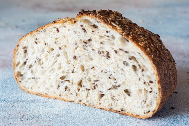 Photo pain frais au levain de grain entier avec des graines de lin, de la farine d'avoine et de graines de sésame sur un fond coloré