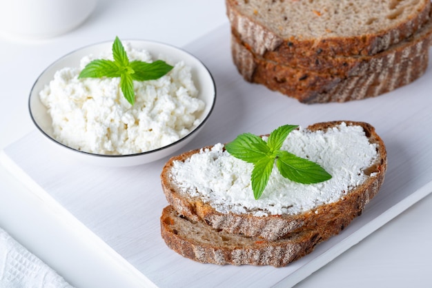 Pain frais aux carottes sur une planche à découper en bois blanc avec du fromage blanc