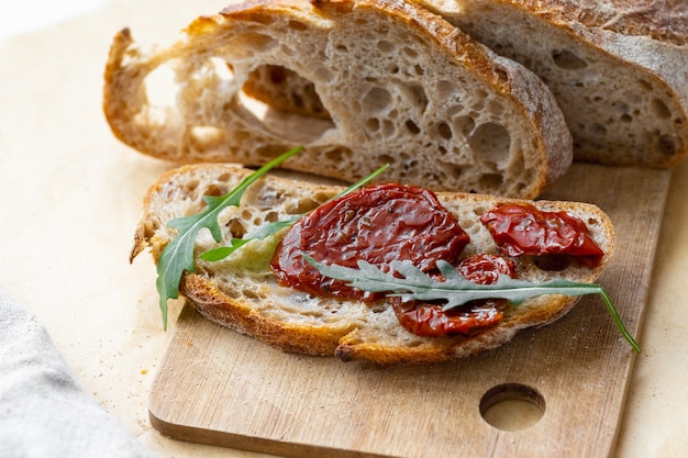 Pain frais aux tomates séchées et à la roquette. déjeuner sain et délicieux, menu végétalien, fruits et légumes. boulangerie, pain frais qui a été cuit à la maison ou dans une pâtisserie