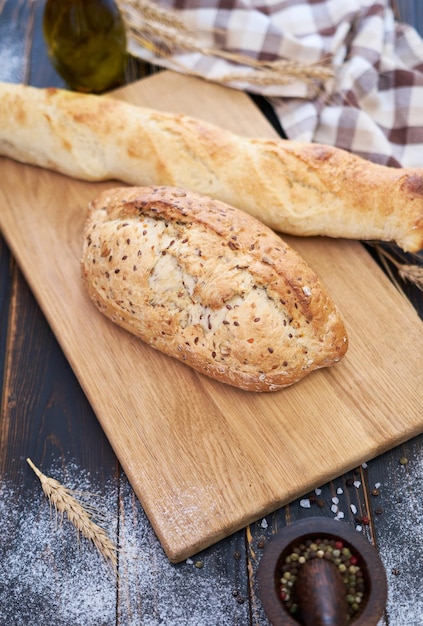 Pain frais et baguette sur une planche à découper en bois à la table de la cuisine