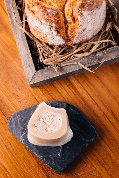 Pain frais cuit sur de la paille dans une boîte en bois servi avec du beurre fait maison.