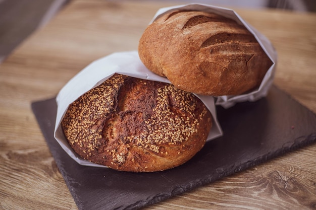 Pain frais dans un sac en papier sur une table en bois Le concept de pain sans gluten de produits naturels