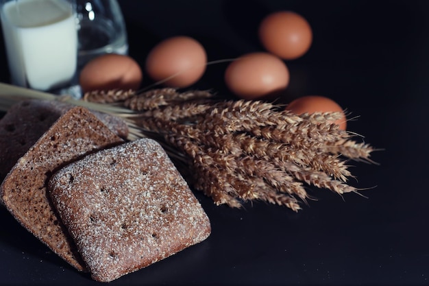 Pain frais avec du blé et du gluten sur une table noire Concept de boulangerie et d'épicerie Sortes fraîches et saines de seigle et de pains blancs gros plan Pain frais fait maison avec des céréales