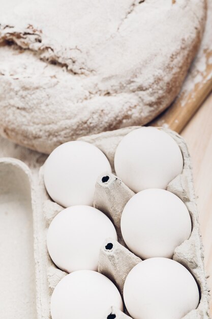 Pain frais, farine et œufs sur une table en bois. Lumière douce