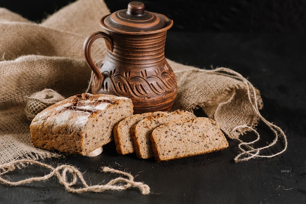 Pain frais avec pot et tissu sur le fond en bois noir