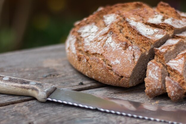 Pain frais en tranches et couteau sur une planche à découper en bois rustique à l'extérieur