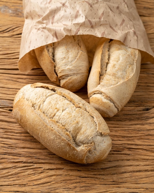 Pain français à grains entiers pain salé ou pistolet sur un sac en papier sur une table en bois