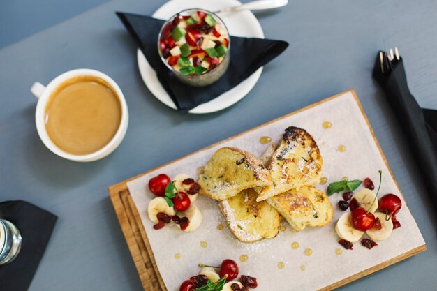 Pain frit avec du sucre à la décoration de bananes et de cerises hachées