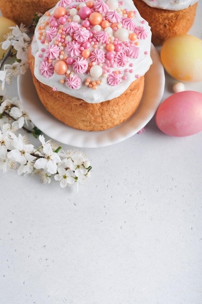 Pain ou gâteaux sucrés traditionnels de Pâques avec glaçage blanc et décor de sucre oeufs colorés et branche d'arbre de fleurs de cerisier sur tableau blanc Divers gâteaux de Pâques de printemps Joyeuses Pâques mise au point sélective