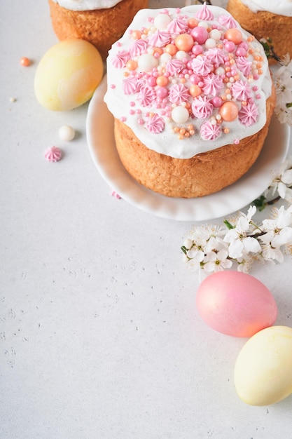 Pain ou gâteaux sucrés traditionnels de Pâques avec glaçage blanc et décor de sucre oeufs colorés et branche d'arbre de fleurs de cerisier sur tableau blanc Divers gâteaux de Pâques de printemps Joyeuses Pâques mise au point sélective