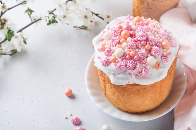 Pain ou gâteaux sucrés traditionnels de Pâques avec glaçage blanc et décor de sucre oeufs colorés et branche d'arbre de fleurs de cerisier sur tableau blanc Divers gâteaux de Pâques de printemps Joyeuses Pâques mise au point sélective