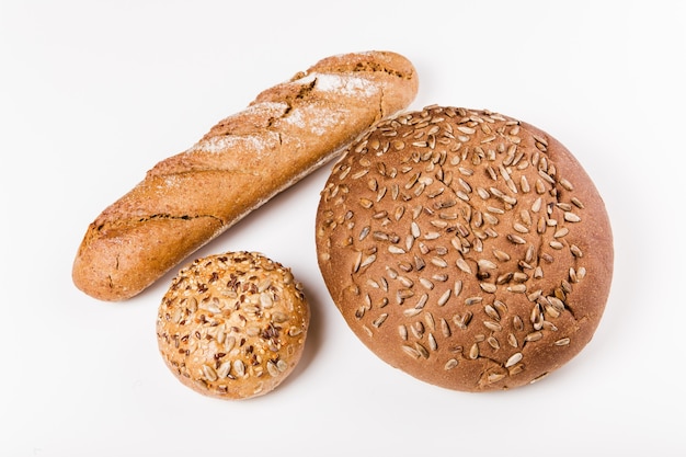 Pain de grains entiers, petit pain, baguette aux graines sur le blanc.