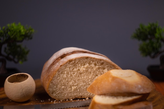 Le pain de grains entiers se trouve sur une assiette en bois de cuisine tenant un couteau de coupe doré. Pain frais sur le