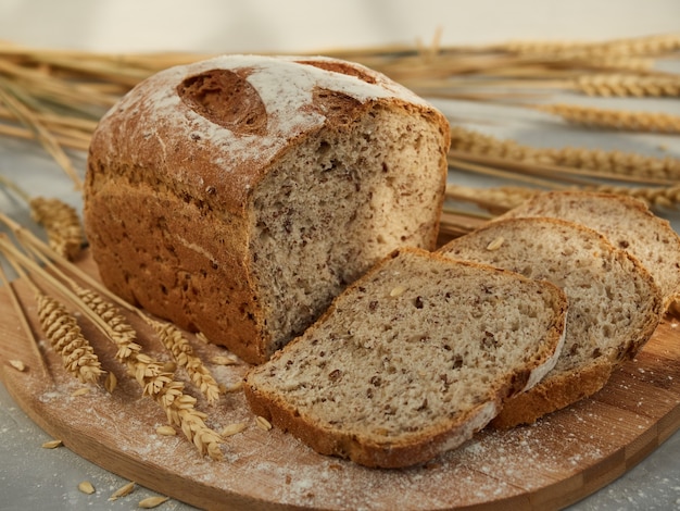 Pain de grains tranché, sur une planche de bois avec des épis et des grains