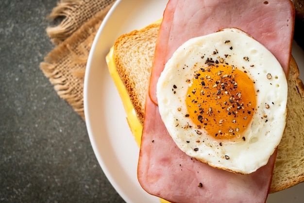 Pain grillé au fromage garni de jambon et œuf au plat avec saucisse de porc